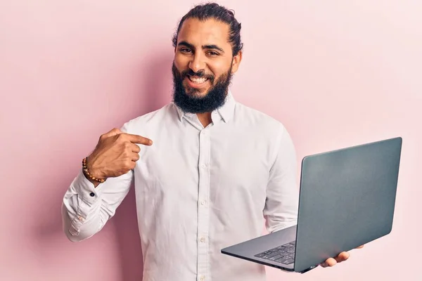 Młody Arabski Człowiek Trzyma Laptop Wskazując Palcem Jeden Uśmiech Szczęśliwy — Zdjęcie stockowe