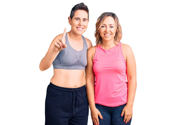 Couple Women Wearing Sportswear Showing Pointing Finger Number One While — Stock Photo, Image