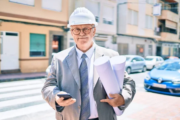 Senior Uomo Architetto Dai Capelli Grigi Possesso Cianografie Utilizzando Smartphone — Foto Stock