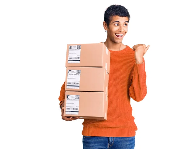 Young African Amercian Man Holding Delivery Package Pointing Thumb Side — Stock Photo, Image