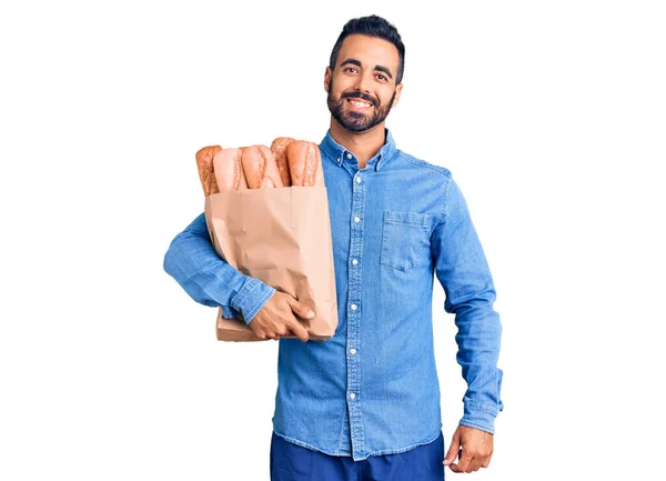 Jovem Hispânico Homem Segurando Saco Com Pão Olhando Positivo Feliz — Fotografia de Stock