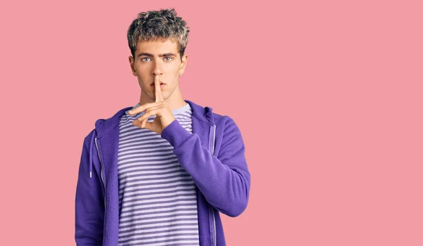 唇に指で静かになるように頼むカジュアルな紫色のスウェットシャツを着た若いハンサムな男 沈黙と秘密の概念 — ストック写真