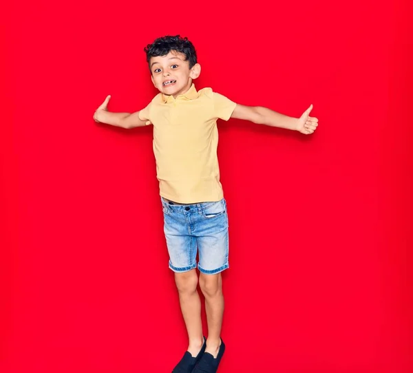 Adorable Niño Con Ropa Casual Saltando Sobre Fondo Rojo Aislado — Foto de Stock