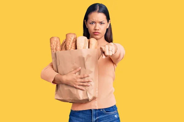 Молодая Красивая Латинская Девушка Держит Бумажный Пакет Хлебом Указывая Пальцем — стоковое фото