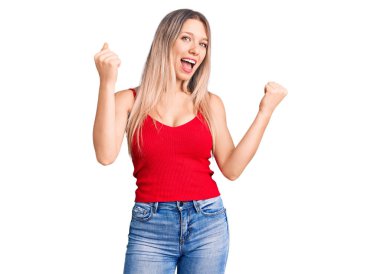 Genç ve güzel sarışın kadın gündelik kıyafetler giyiyor gururla bağırıyor, zaferi kutluyor ve kollarını kaldırarak başarıyı kutluyor. 