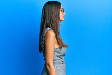 Genç İspanyol kadın iş elbisesi ve gözlük takıyor. Taraf arıyor, rahat poz veriyor. Kendine güvenen bir gülümsemesi var.. 