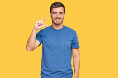 Yakışıklı, günlük kıyafetler giyen, gülümseyen, kendine güvenen, el hareketi yapan, parmaklarıyla işaret yapan, kameraya bakan beyaz bir adam. ölçüm kavramı. 