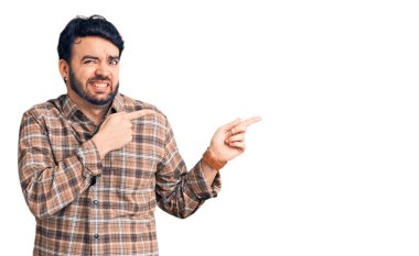 Gündelik kıyafetler giyen genç İspanyol bir adam iki eliyle endişeli ve endişeli bir ifadeye işaret ediyor. 