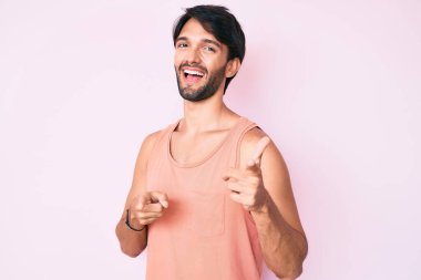 Sıradan kıyafetler giyen yakışıklı İspanyol adam mutlu ve komik yüzlü parmaklarını kameraya doğrultuyor. iyi enerji ve titreşimler. 