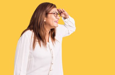 Gözlük ve gözlük takan genç ve güzel bir kadın yan tarafa bakıyor, kendine güvenen ve neşeli..