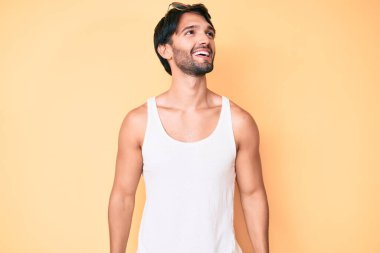 Yaz bakışı ve güneş gözlüğü takan yakışıklı İspanyol adam yüzünde gülümseme, doğal bir ifade ile yan yana bakıyor. Kendinden emin gülen. 