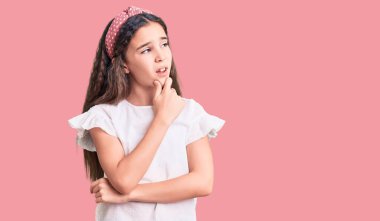 Beyaz bir tişört giyen tatlı İspanyol kız bir soru hakkında endişeli ve gergin bir şekilde düşünüyor. 