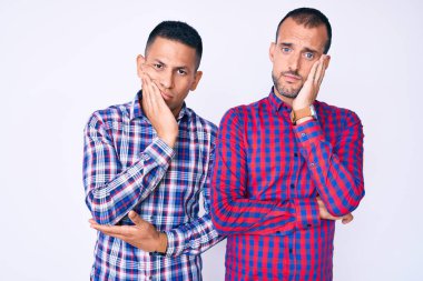 Genç eşcinsel iki adam gündelik giysiler giyip kollarını kavuşturarak depresyondan sıkılmış ve yorgun görünüyorlar.. 