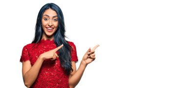 Zarif bir tişört giyen güzel İspanyol kadın gülümseyip kameraya bakıyor ve iki eliyle ve parmaklarıyla kenarı işaret ediyor.. 