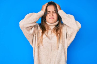 Güzel beyaz kadın yün kazak giyiyor. Baş ağrısı çekiyor. Acı ve migren yüzünden stresli. Eller başının üstünde.. 