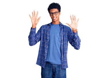 Genç Afro-Amerikalı günlük kıyafetler ve gözlük takmış on numaralı parmaklarıyla onu gösterirken kendinden emin ve mutlu gülümsüyor.. 