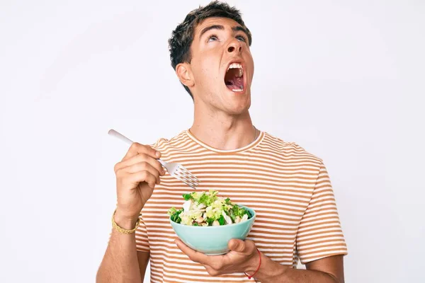 Joven Hombre Guapo Comiendo Ensalada Enojado Loco Gritando Frustrado Furioso —  Fotos de Stock