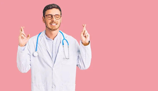 Handsome Young Man Bear Wearing Doctor Uniform Gesturing Finger Crossed — Stock Photo, Image