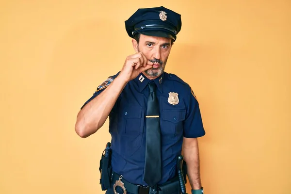 Middle age hispanic man wearing police uniform mouth and lips shut as zip with fingers. secret and silent, taboo talking