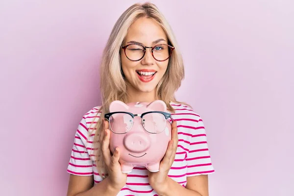 Mooi Kaukasisch Blond Meisje Holding Piggy Bank Met Bril Knipperen — Stockfoto