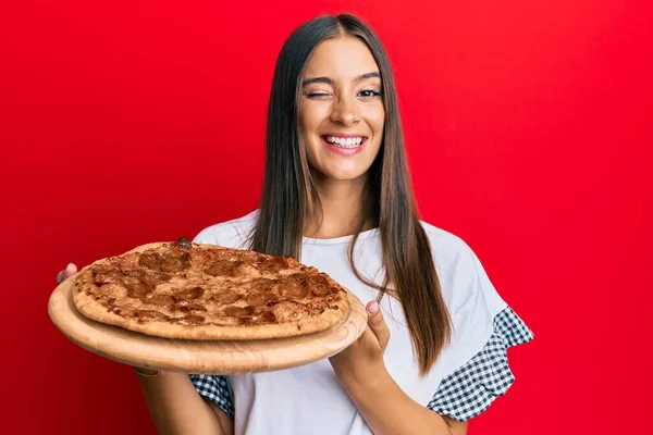 Jovem Hispânica Segurando Pizza Italiana Piscando Olhando Para Câmera Com — Fotografia de Stock