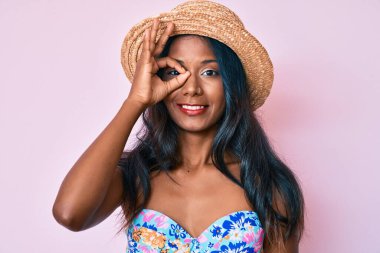 Bikini ve yaz şapkası takan genç Hintli kız gülümsüyor. 