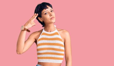 Kısa saçlı, esmer bir kadın. Günlük giysiler giyip, el ve parmaklarını silah gibi kullanıyor. İntihar jesti.. 