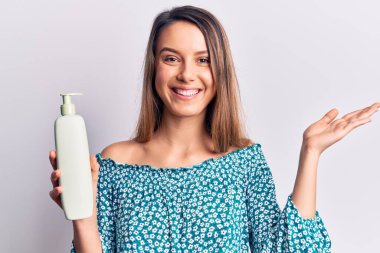 Genç, güzel bir kız elinde bir şişe krem losyon tutarak başarıyı mutlu bir gülümsemeyle ve kazanan yüz ifadesiyle kutluyor. 