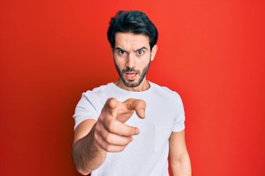 Latin asıllı genç adam, sıradan beyaz tişörtler giyerek kameraya kızgın ve sinirli bir şekilde bakıyor. 