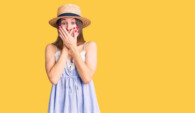 Yaz şapkası takan güzel esmer bir kadın yanlışlıkla elleriyle ağzını kapatırken şok oldu. gizli kavram. 