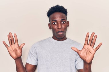 Sıradan kıyafetler giyen, korku ifadesinden korkan ve dehşete düşmüş genç Afro-Afrikalı Amerikalı adam el kol hareketi yapmayı kes, şok içinde bağır. panik konsepti. 