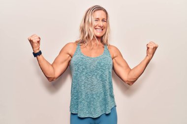 Orta yaşlı beyaz kadın spor giysisi giyiyor. Çok mutlu ve heyecanlı. Kolları havada, gülümseyen ve başarı için çığlık atan kazanan bir jest yapıyor. kutlama konsepti. 