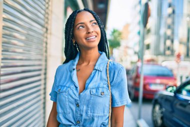Genç Afrikalı Amerikalı kadın gülümseyerek şehirde mutlu mesut yürüyor..