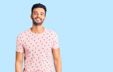 Genç, yakışıklı, günlük kıyafetler giyen, pozitif ve mutlu görünen, kendine güvenen, gülümseyen, dişlerini gösteren bir İspanyol. 