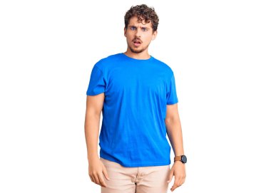 Kıvırcık saçlı, şaşkın suratlı, sıradan kıyafetler giyen, kuşkucu ve alaycı bakışlı, ağzı açık, şaşırmış genç bir adam. 