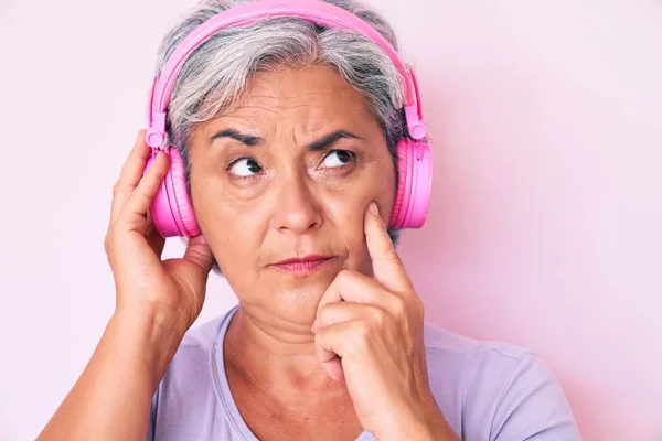 Senior Hispanic Woman Listening Music Using Headphones Serious Face Thinking — Stock Photo, Image