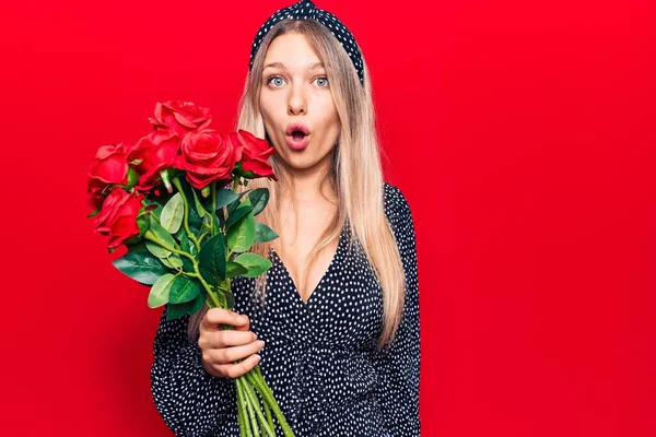 Młoda Blondynka Trzyma Kwiaty Przestraszony Zdumiony Otwartymi Ustami Dla Zaskoczenia — Zdjęcie stockowe