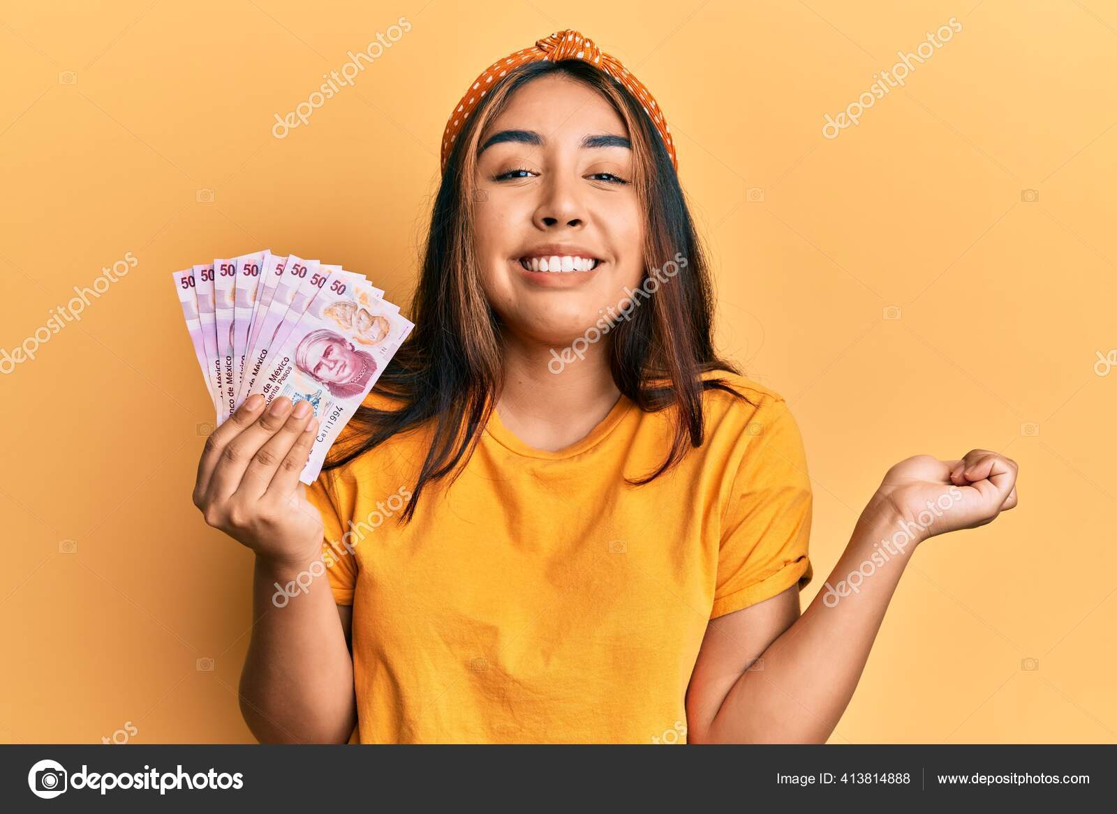 拿着墨西哥比索钞票的年轻女子自豪地尖叫着高举双臂庆祝胜利和成功——图库图片© Krakenimages.com #413814888