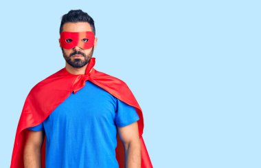 Genç İspanyol adam süper kahraman kostümü giyiyor ve yüzünde ciddi bir ifade var. Basit ve doğal bir şekilde kameraya bakıyorsun.. 