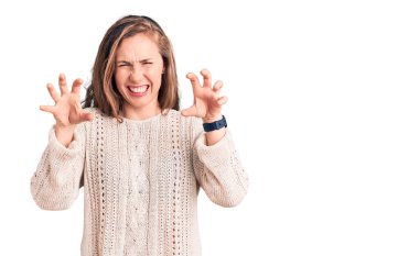 Genç, güzel, sarışın bir kadın sıradan bir süveter giyip gülümsüyor. Pençe hareketlerini kedi gibi yapıyor. Agresif ve seksi bir ifade. 