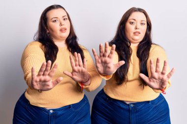 Genç ve cüsseli ikizler günlük kıyafetler giyip avuç içi hareketlerini durduruyorlar. Öfkeli ve hayal kırıklığı dolu bir ifade takınıyorlar. 