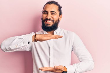 Gündelik giysiler giyen genç bir Arap. Elleriyle hareket ediyor. Büyük ve büyük beden işareti, ölçü işareti gösteriyor. Kameraya bakıp gülümsüyor. ölçüm kavramı. 