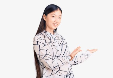 Genç, güzel, Çinli bir kadın, rahat bir tişört giyip gülümseyerek içeri girmeye davet ediyor. 