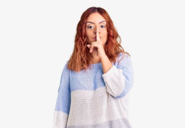 Gündelik giysiler giyen genç Latin kadın parmakları dudaklarında sessiz olmak istiyor. sessizlik ve gizli konsept. 