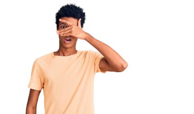 Genç, Afro-Amerikan bir adam günlük giysiler giymiş. Şoka girmiş, yüzünü ve gözlerini kapamış, utanmış bir ifadeyle parmaklarının arasından bakıyor.. 