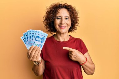 Güzel orta yaşlı bir kadın elinde 10 yuan Çin banknotuyla mutlu mesut elini ve parmağını gösteriyor. 