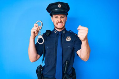 Polis üniforması giyen, elleri kelepçeli genç beyaz bir adam öfkeyle bağırıyor, öfkeyle bağırıyor ve el kaldırıyor. 