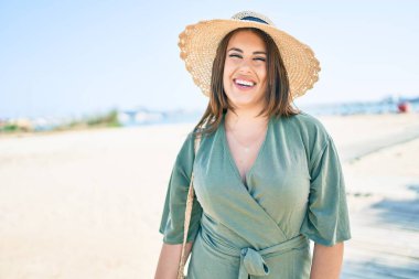 Genç İspanyol kadın tatilde. Gülümsüyor. Kumsalda mutlu yürüyüşler.
