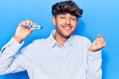 Termometreyi tutan İspanyol genç adam gururla bağırıyor, zaferi kutluyor ve başarıyı kollarını kaldırarak kutluyor. 