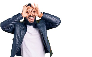 Deri ceket giyen genç bir Arap dürbün gibi jest yapıyor, gözleri parmaklarından bakıyor. çılgın ifade. 